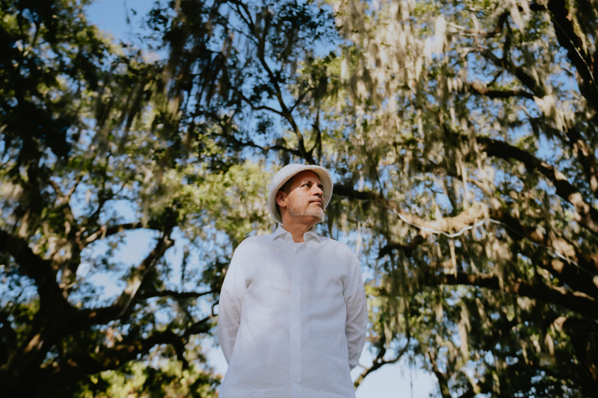 DJ Erick Santero in front of oak trees and wearing a white shirt