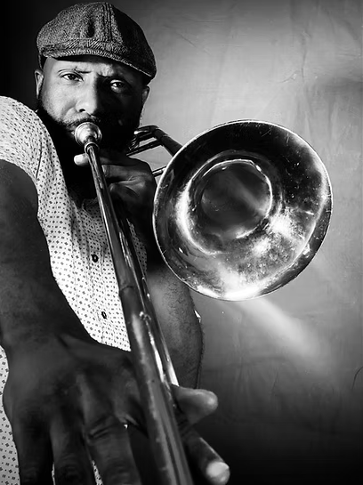 A man in a hat holds a trumpet, likely a musician.